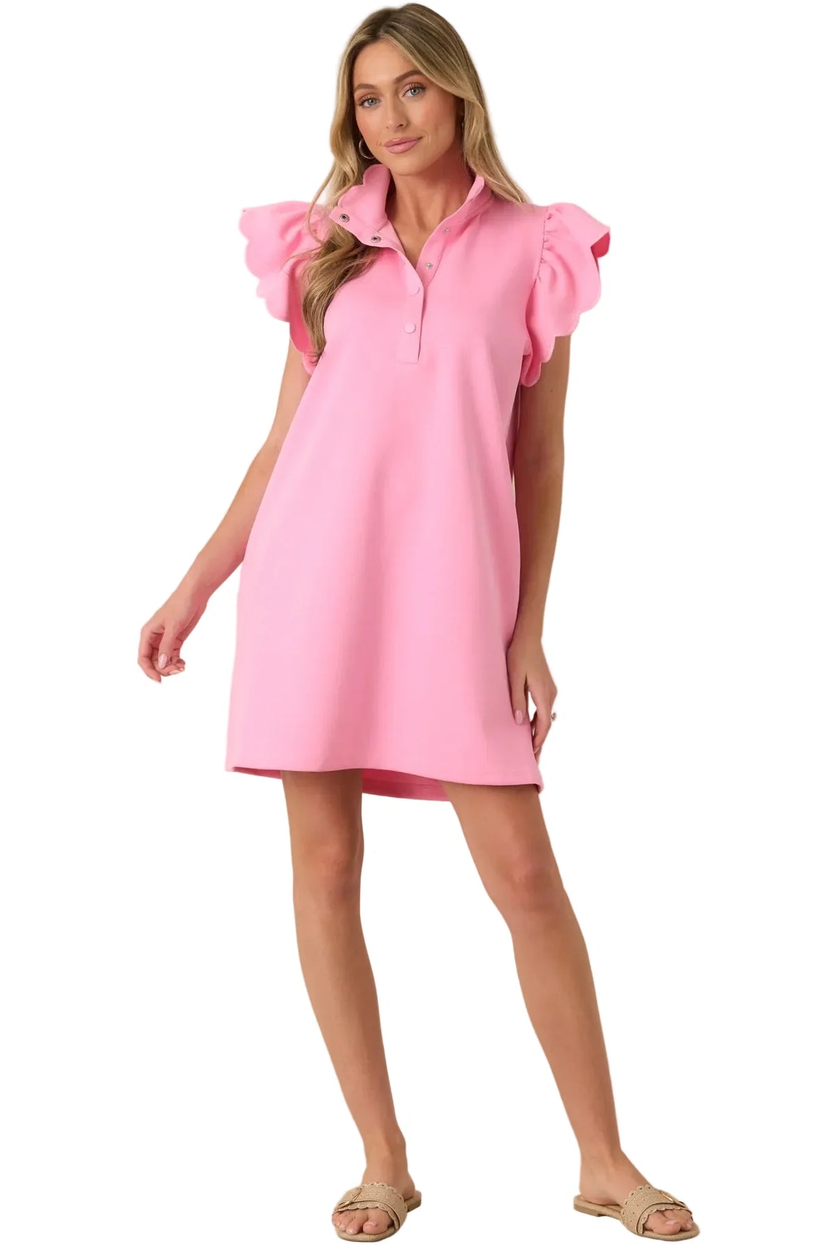 Woman wearing a pink dress with ruffled sleeves against a beige background