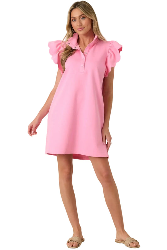 Woman wearing a pink dress with ruffled sleeves against a beige background